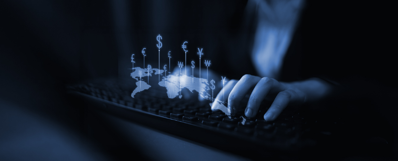 Hands on keyboard with world map and currency symbols representing global finance